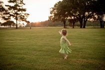 Toddler girl running in grassy field — Stock Photo