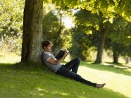 Garçon lisant sous un arbre — Photo de stock