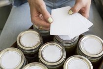 Cropped view of woman labeling jars — Stock Photo