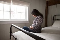 Ожидаемая мать, сидящая на кровати — стоковое фото