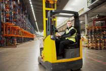 Worker operating forklift in warehouse — Stock Photo