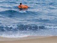Человек, плавающий во внутренней трубе в океане — стоковое фото