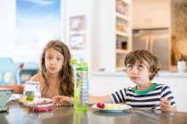 Menino e menina na mesa da cozinha puxando rostos — Fotografia de Stock