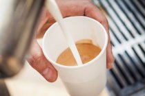 Homem derramando leite em xícara de café — Fotografia de Stock