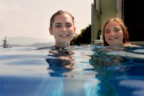 Surface level portrait of teenage girls in outdoor swimming pool — Stock Photo