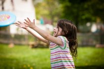 Junges Mädchen wirft Frisbee in Garten — Stockfoto