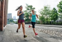 Mujeres jóvenes corriendo en Dumbo, Brooklyn, Nueva York, EE.UU. - foto de stock