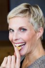 Smiling woman eating snack — Stock Photo