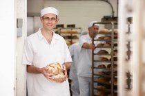 Chef holding loaves of bread in kitchen — Stock Photo