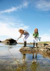 2 girls fishing in rock pool — Stock Photo