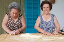 Пожилые женщины вместе делают макароны — стоковое фото