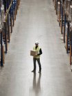 Worker carrying box in warehouse — Stock Photo