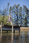 Ragazzo che salta nel lago dal molo — Foto stock