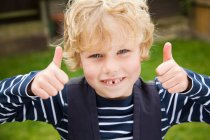 Sorrindo menino dando polegares para cima ao ar livre — Fotografia de Stock