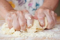 Cropped image of senior woman kneading dough — Stock Photo