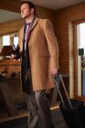Businessman rolling luggage in lobby, focus on foreground — Stock Photo