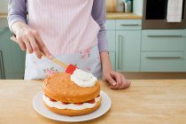 Mid section of woman making cake in kitchen — Stock Photo
