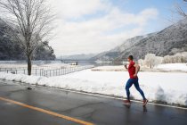 Corredor masculino correndo ao longo da estrada no inverno, Lago Kawaguchiko, Monte Fuji, Japão — Fotografia de Stock