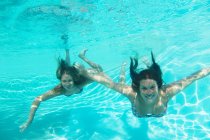 Madre e hija nadando en la piscina - foto de stock
