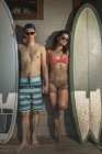 Porträt eines coolen jungen Surfer-Paares, das auf der Veranda steht, Rockaway Beach, New York State, Vereinigte Staaten — Stockfoto
