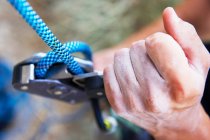 Primo piano visione parziale di persona che tiene moschettone durante l'arrampicata, concetto di sport estremo — Foto stock