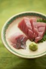 Prato de peixe fatiado cru com folhas e wasabi — Fotografia de Stock