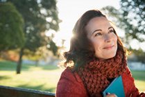 Sorrindo mulher segurando livro ao ar livre — Fotografia de Stock