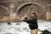 Человек ловит лосося в реке — стоковое фото