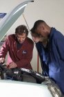 Вчитель допомагає студентам з двигуном автомобіля — стокове фото