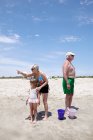 Mulher sênior com neta apontando e olhando para fora na praia — Fotografia de Stock