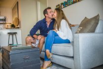 Mann küsst Ehefrau auf Sofa auf die Wange — Stockfoto
