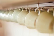 Cups hanging on rack — Stock Photo