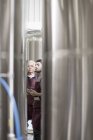 Пивовари в пивоварні стоять поруч з резервуарами з нержавіючої сталі — стокове фото