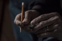 Nahaufnahme männlicher Hände, die einen Bleistift und ein Stück Holz halten — Stockfoto