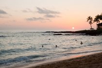 Les gens dans la mer au coucher du soleil — Photo de stock