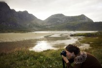 Woman taking a photograph in mountain landscape — Stock Photo