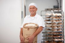 Chef portant un sac de farine dans la cuisine — Photo de stock