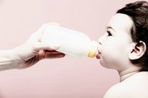 Retrato de la niña bebiendo leche del biberón - foto de stock