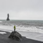 Jeune touriste mâle regardant vers la mer depuis la formation de rochers, Reynisfjara, Islande — Photo de stock