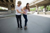 Garçon aider petite amie à patiner — Photo de stock