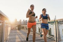 Two friends exercising together, running outdoors by river — Stock Photo