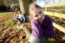 Mädchen sitzt auf Baumstamm auf Wiese — Stockfoto