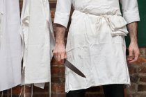 Imagem cortada de açougueiro de pé com faca — Fotografia de Stock