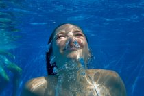 Vista de la cabeza y el hombro bajo el agua de la niña nadando en la piscina - foto de stock