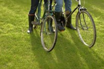 Close-up, duas pessoas + bicicleta velha grama — Fotografia de Stock
