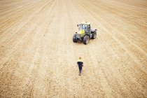 Agricoltore a piedi fino al trattore nel campo coltivato — Foto stock