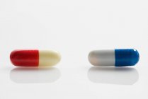 Two red and blue capsules on white background — Stock Photo