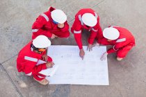 Workers with blueprints at oil refinery — Stock Photo