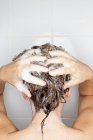 Вид ззаду жінки, що миє волосся в душі — стокове фото
