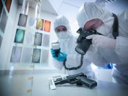 Forensic scientists photographing fingerprints on gun in laboratory — Stock Photo